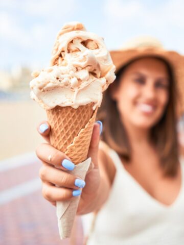 A woman holding an ice cream dessert on a sunny day with Orlando in the background.