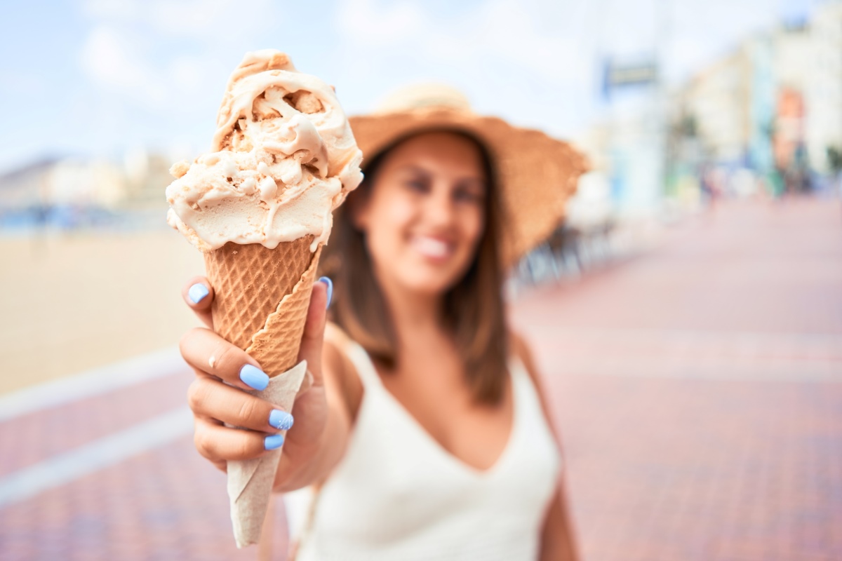 A woman holding an ice cream cone on a sunny day with Orlando in the background.