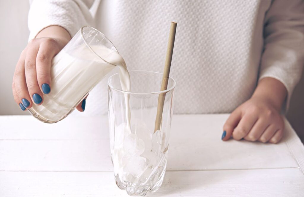 Milk being poured over a glass of ice.