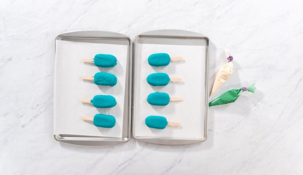 Several cake popsicles on a tray dipped in blue chocolate.