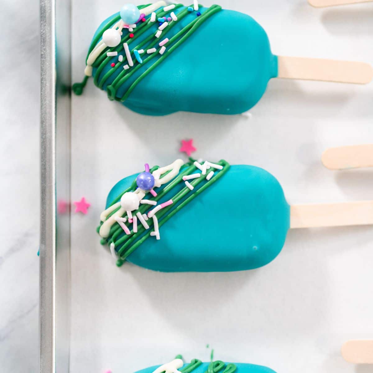 Blue cake popsicles on a cookie sheet.