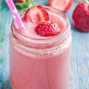 A creamy strawberry smoothie in a mason jar glass.