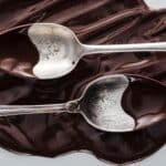 Two spoons showing tempered and untempered chocolate.