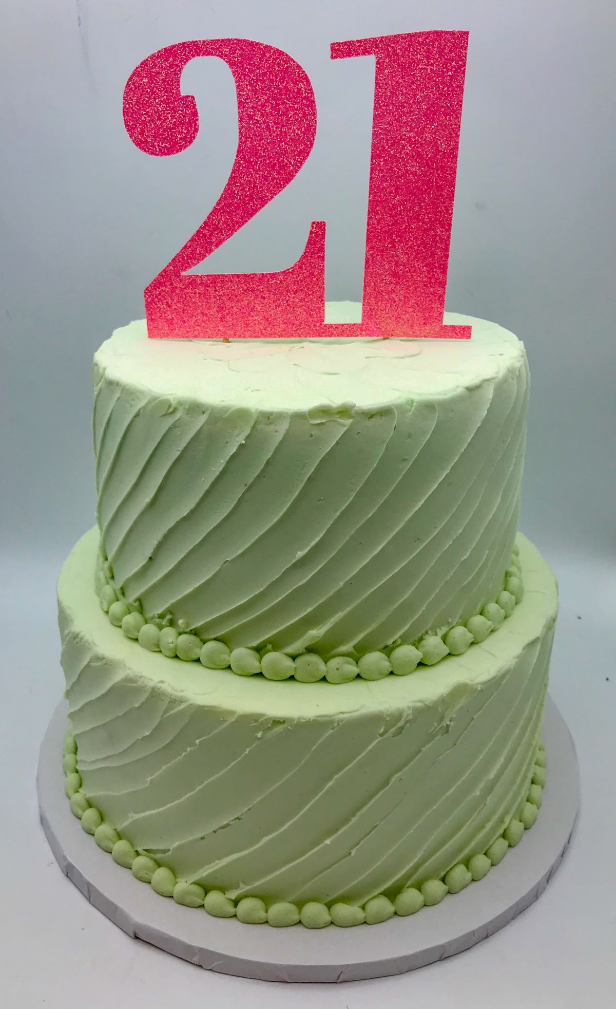 A light green cake with a minimalist diagonal frosting texture and a 21 cake topper.