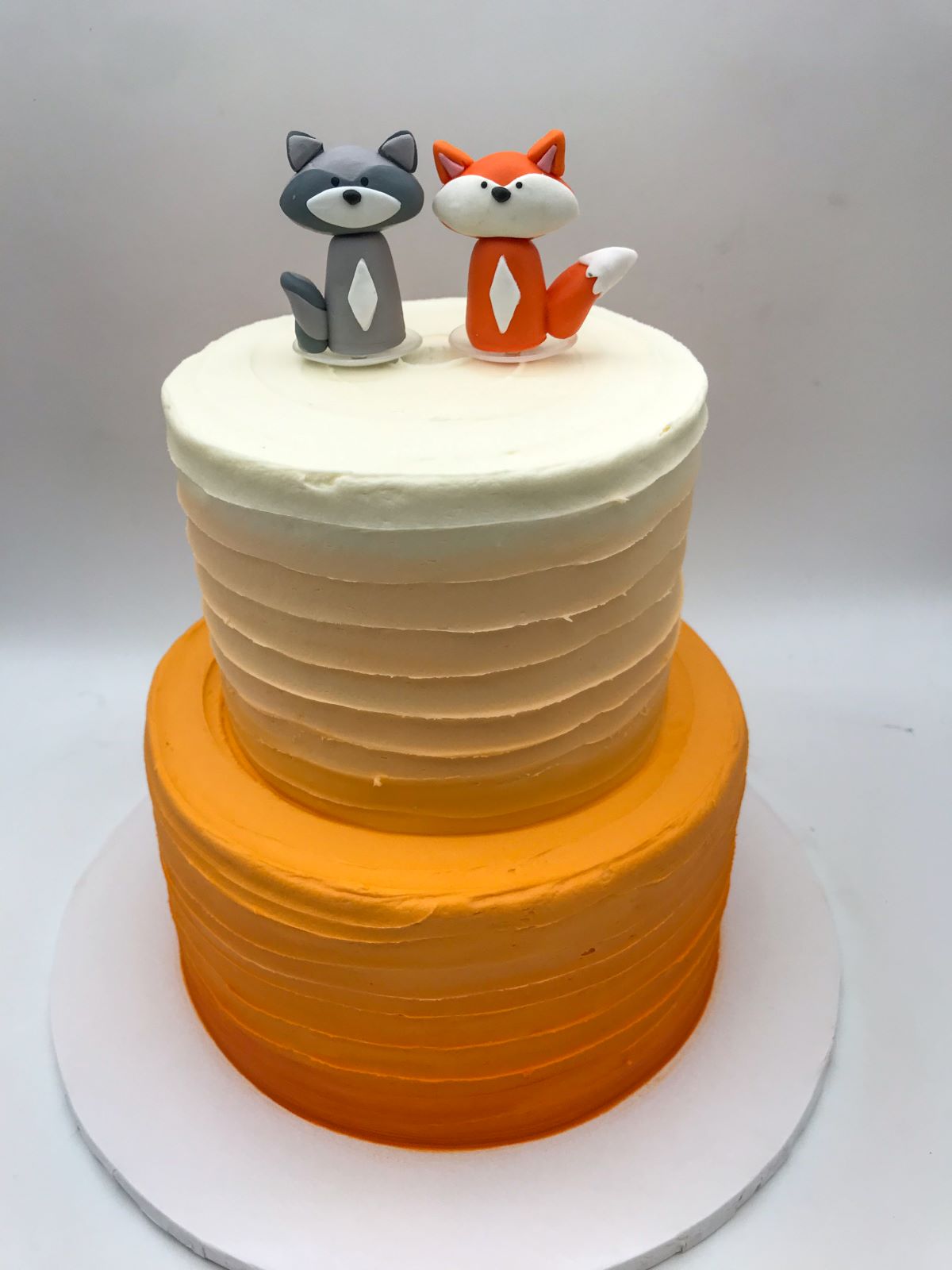 An orange ombre simple cake design with fox cake toppers.