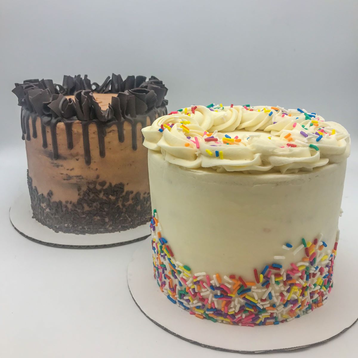 Two minimalist cakes decorated with sprinkles or choccolate curls.