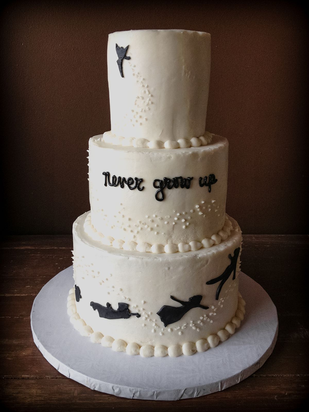 A baby shower cake with a minimalist cake design for a Peter Pan theme.
