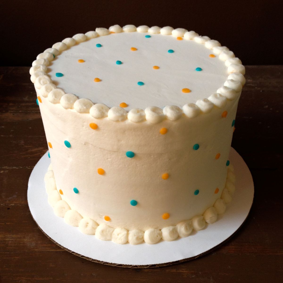 A simple white cake with a dainty minimalist dot pattern.